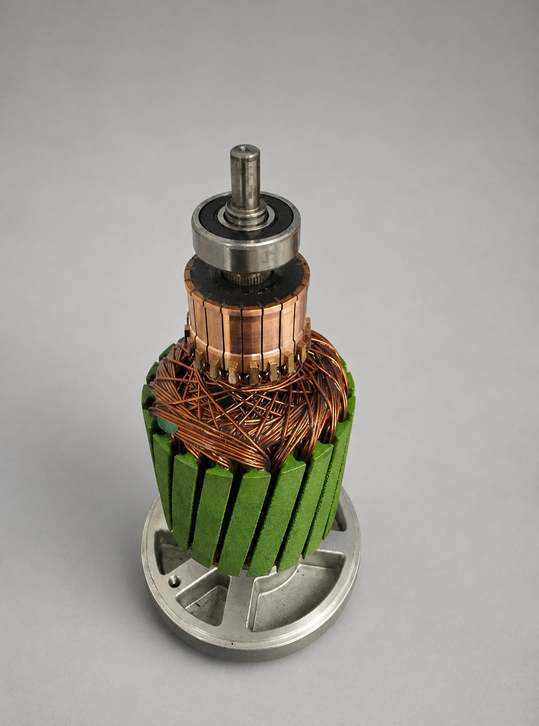 A rebuilt AutoStore robot drive motor armature standing on its end bracket, with a freshly machined commutator and a new bearing fitted
