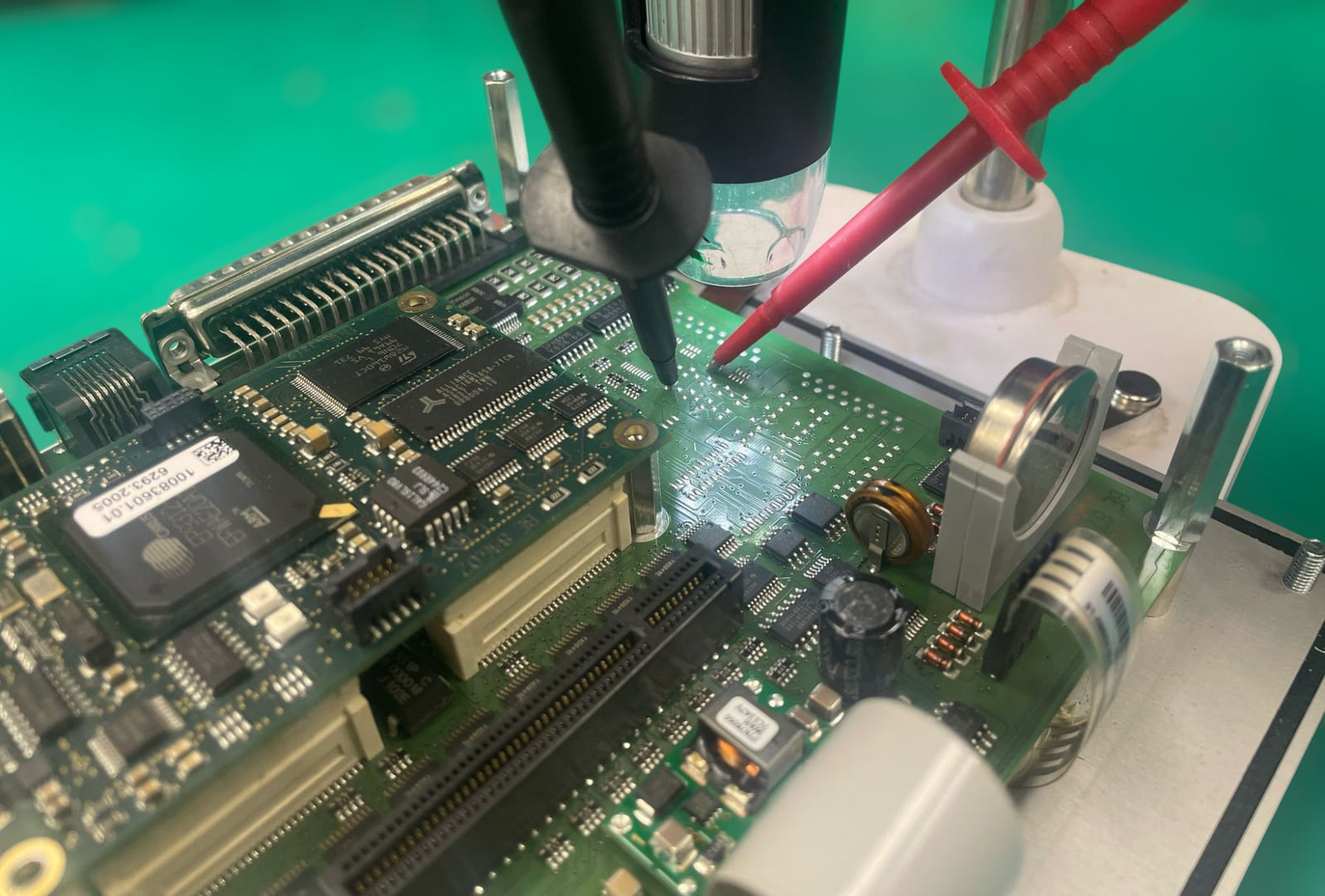 An industrial control board under a bench microscope with test probes placed on it during fault diagnosis