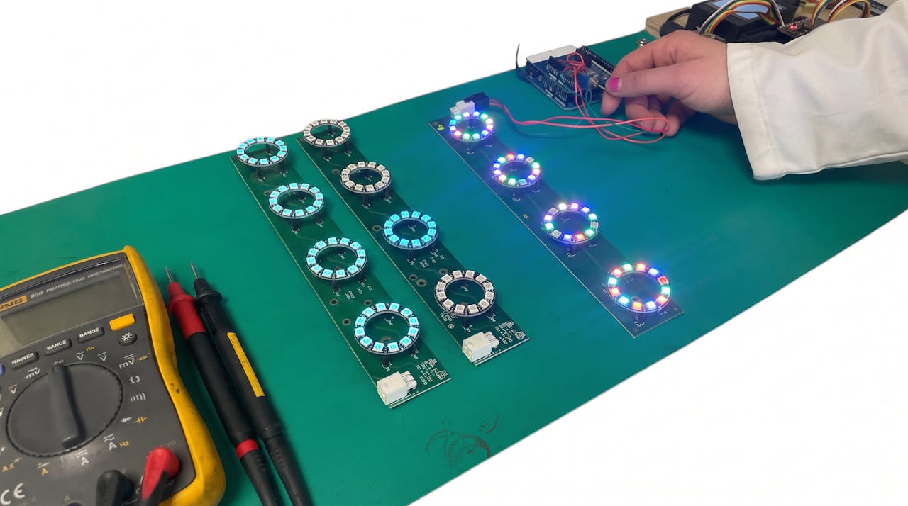 LED ring backplane assemblies under test on an ESD mat, with a multimeter alongside