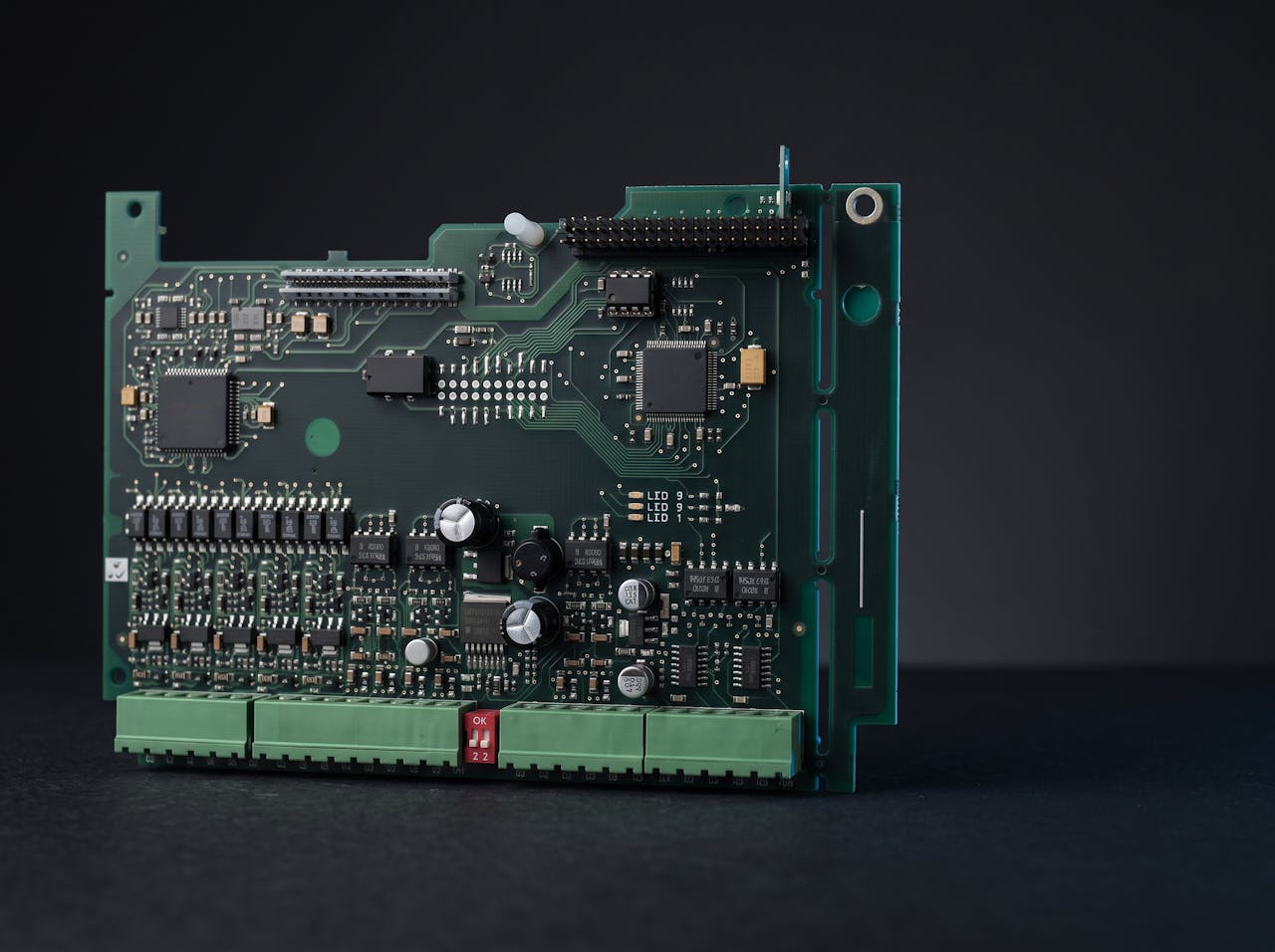 A multilayer industrial control PCB stood on edge, showing surface-mount devices and terminal connectors